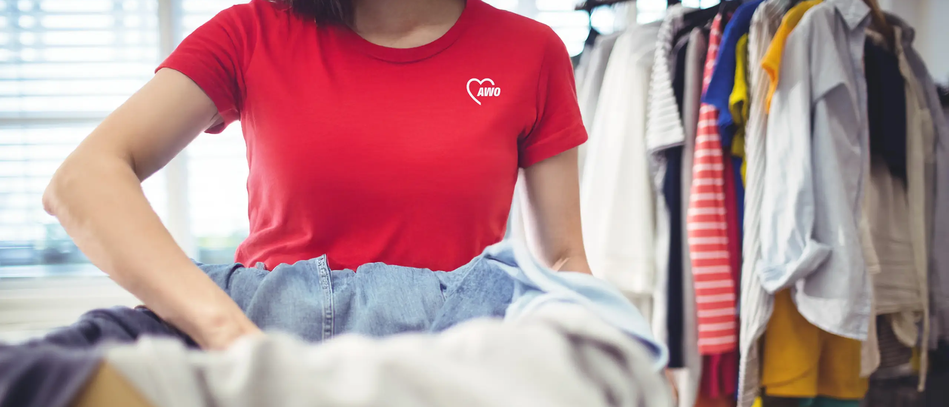 Eine Frau im roten AWO-Shirt packt Kleiderspenden in einen Karton | © https://de.freepik.com/
